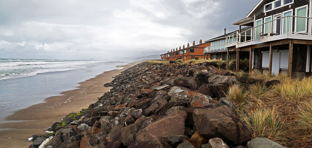 Oceanfront homes with boulders piled along the front to protect them from erosion.