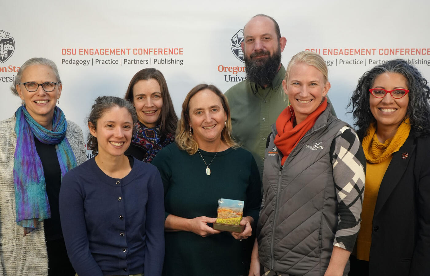 A group of people smile at the camera holding an award.