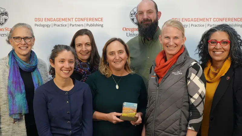 A group of people smile at the camera holding an award.