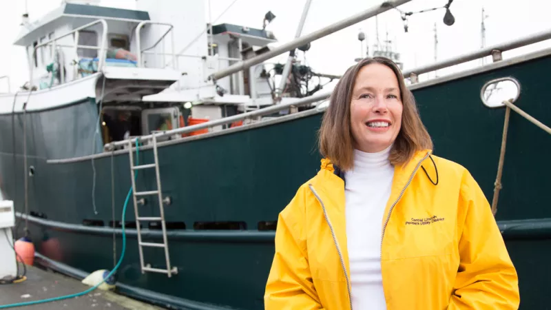 Michele Longo Eder stands in front of a fishing boat