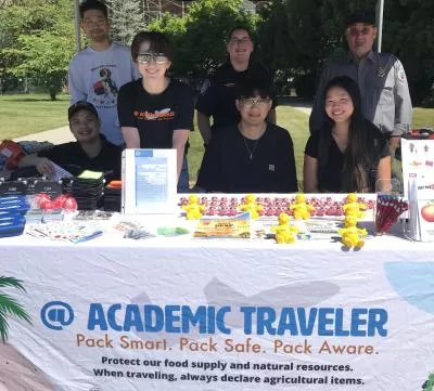Students at a tabling event smile at camera.