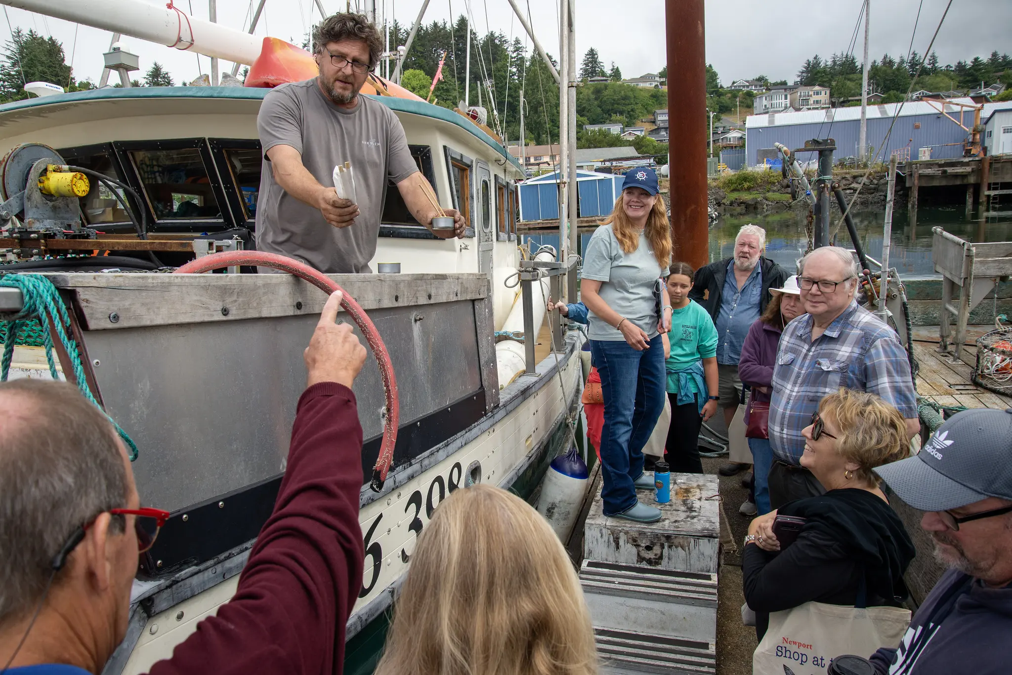 A group of people standing beside a fishing boat on a dock.