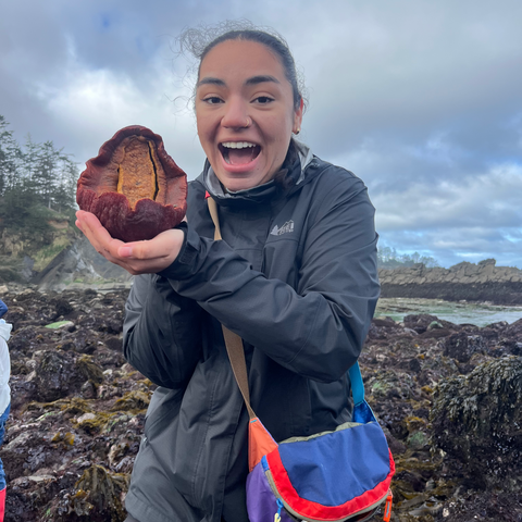 A person holds a fruit and smiles.