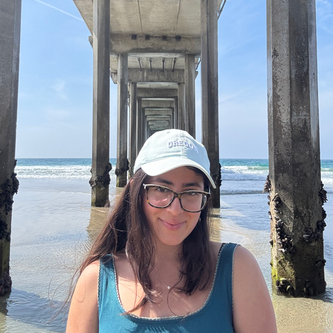 A person standing under a pier and smiling.