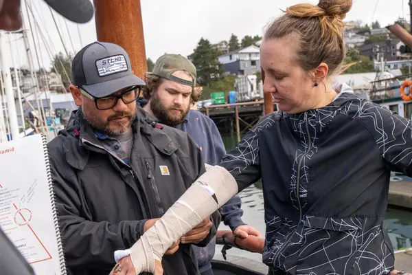 A person wearing a cast holds out their arm while it is examined by someone else.