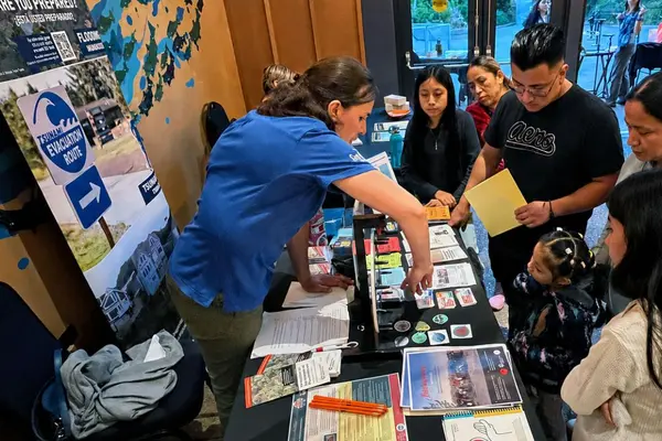 A group of people gather around a table with materials on it.