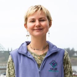 A woman wearing a purple vest smiles.