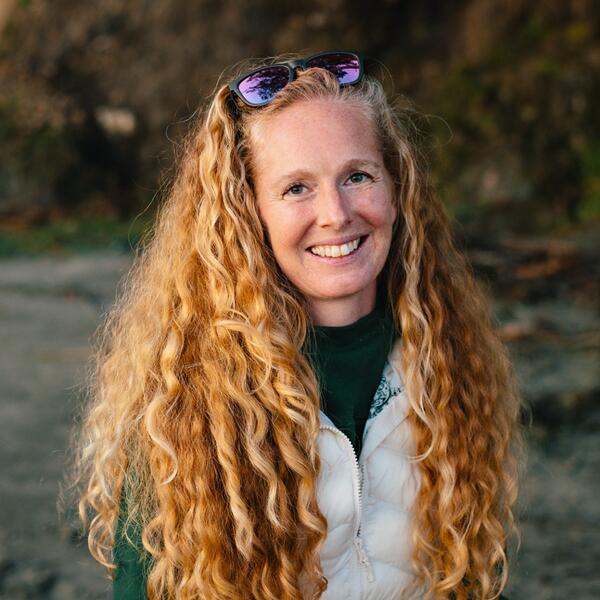 A person with long curly hair smiles at the camera.