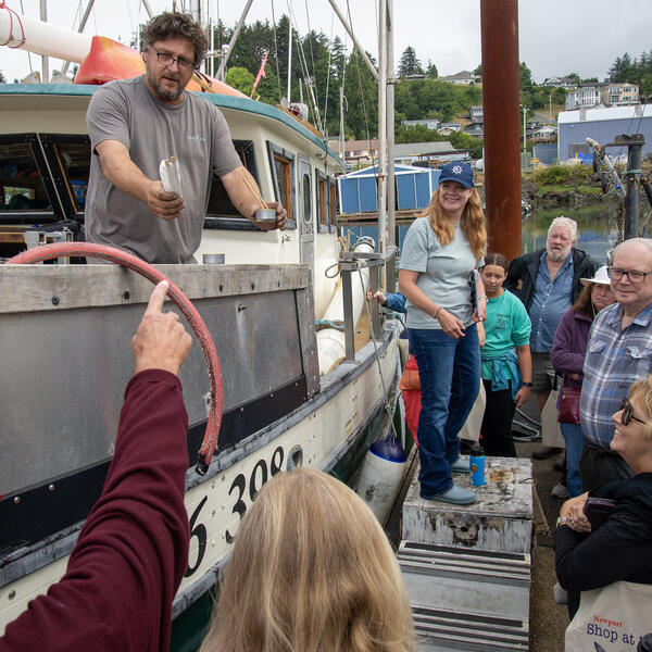A group of people standing beside a fishing boat on a dock.