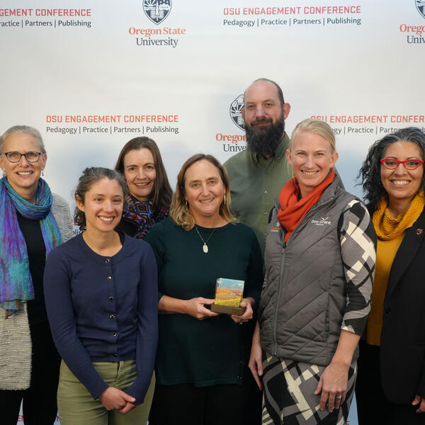 A group of people smile at the camera holding an award.
