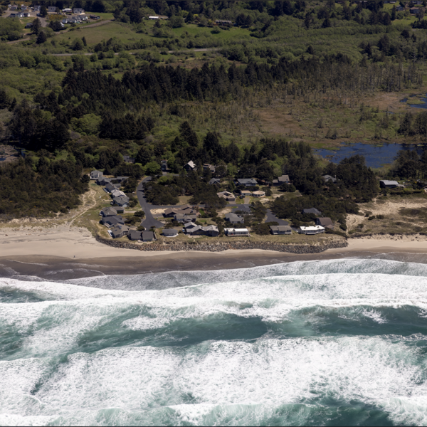 Waves was ashore on a beach in front of houses protected by rip rap.