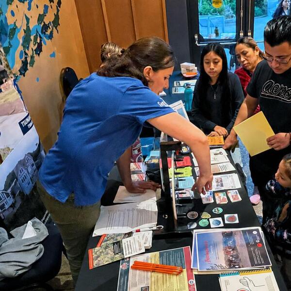 A group of people gather around a table with materials on it.
